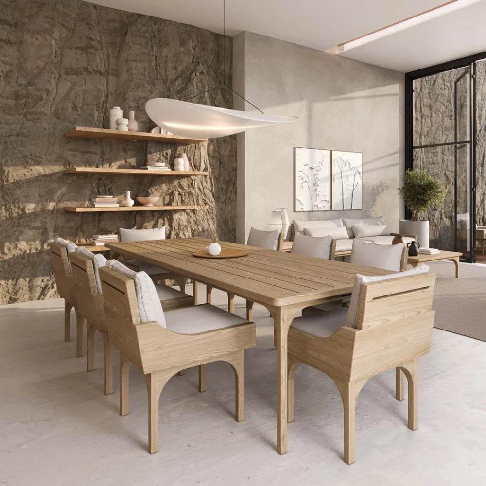 Modern dining room with wooden table and chairs against a stone wall.