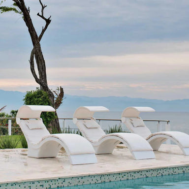 Three white pool chaise loungers with headrest covers arranged beside a swimming pool.