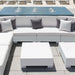 White outdoor sectional sofa with gray accent pillows, matching white coffee tables, and a blue tiled pool deck in the background.