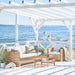 Natural rattan outdoor lounge chair with white cushions beside a matching 3-seater sofa and teak coffee table.