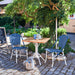 Blue and white rattan outdoor dining side chair beside a square teak café table in a garden setting.