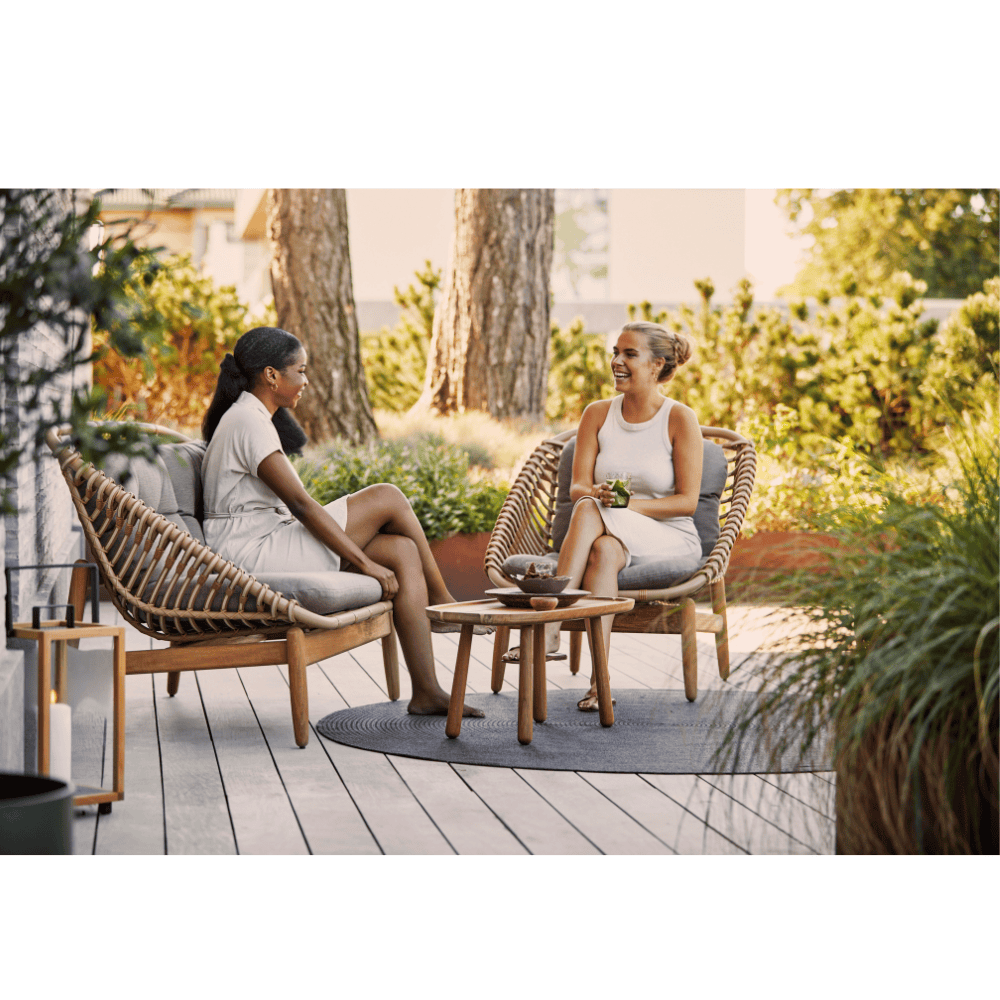 Boxhill's String light brown outdoor 2-seater sofa-teak frame with String lounge chair, teak side table and 2 women sitting