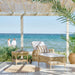 Natural rattan outdoor square side table with a woven lower shelf beside a chaise lounge.