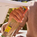 Hand holding a bottle of Tecate beer with a blurred outdoor background