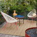 Rectangular outdoor rug in brown woven material, placed under chairs and table for patio setting