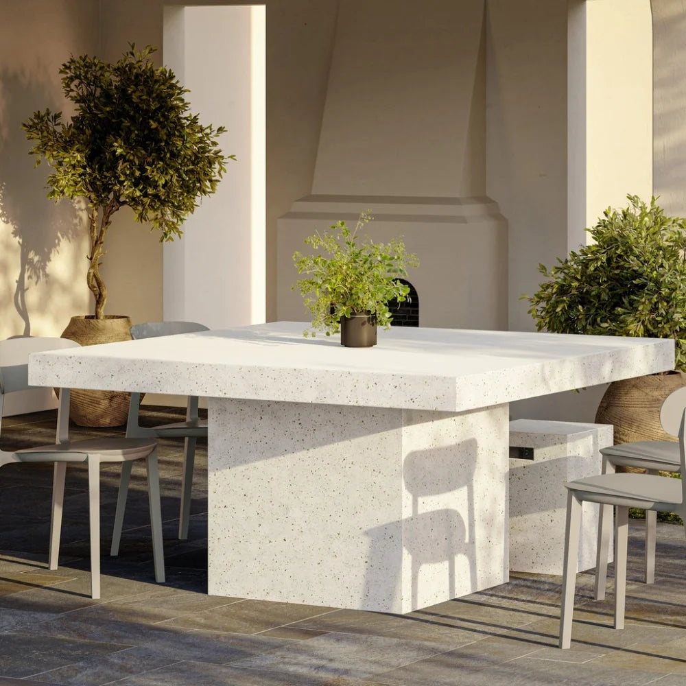 Patio dining area with square white speckled outdoor dining table, gray chairs and potted plants