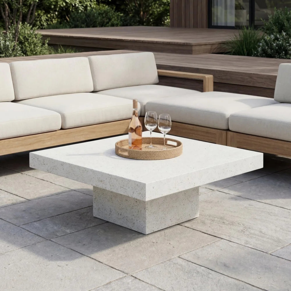 Patio seating with square white speckled concrete coffee table, wooden sectional sofa with beige cushions, and wooden platform