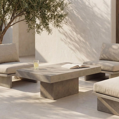 Patio seating with modern gray  concrete rectangular outdoor coffee table surrounded by gray cushioned chairs