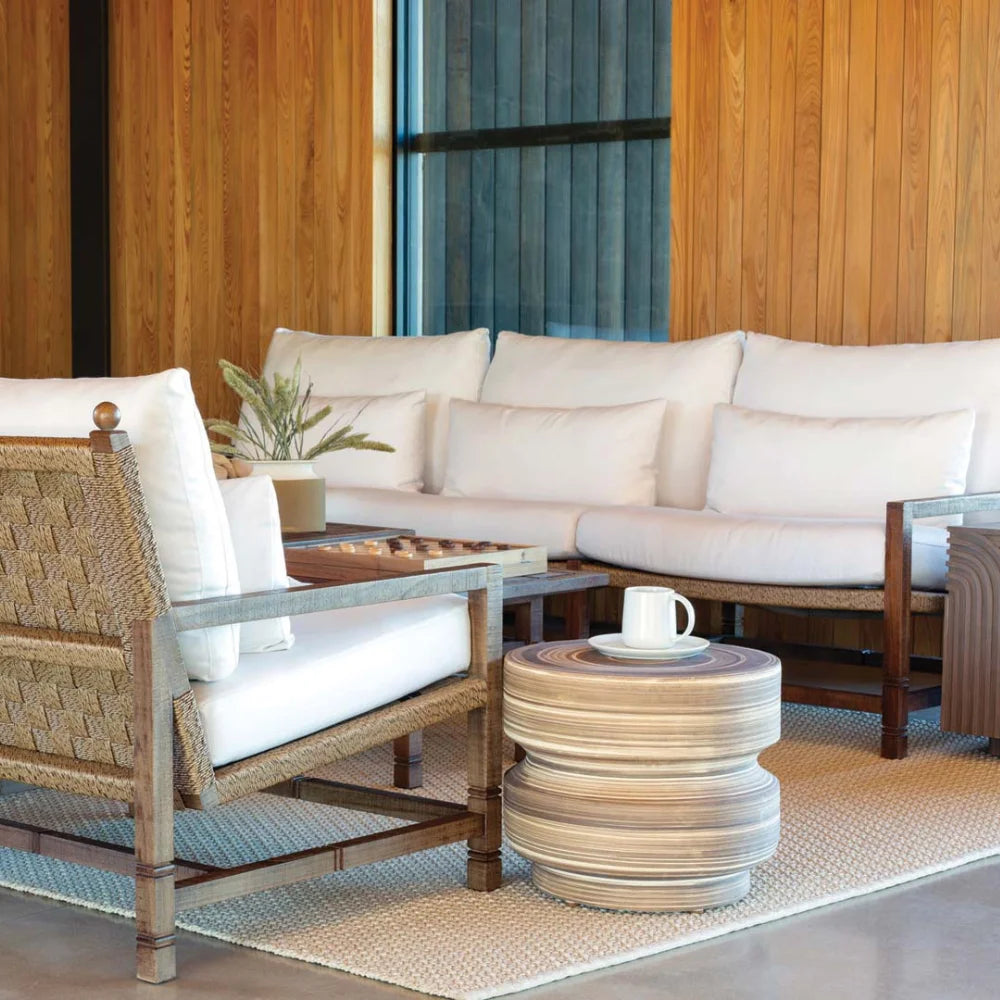 Outdoor seating area with white sofa, wicker chairs, and a striped rug.