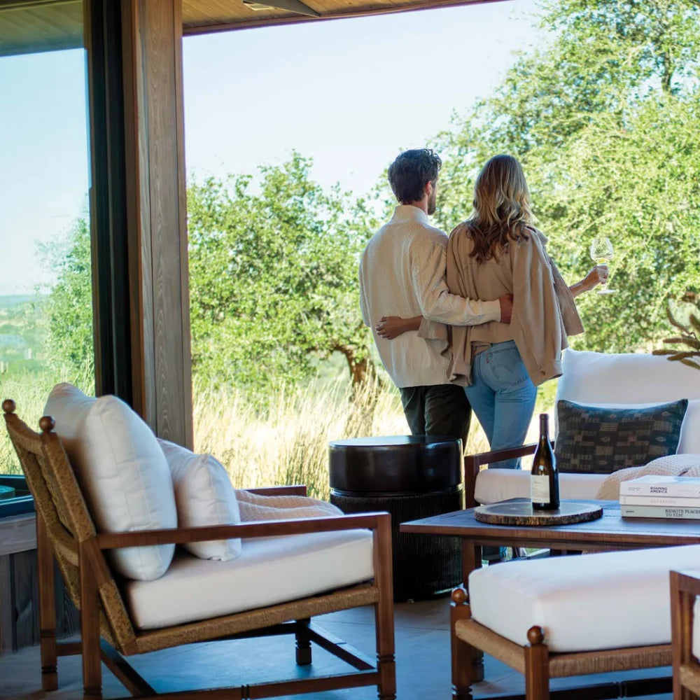 Couple standing on a patio with a scenic view, holding hands and looking out towards nature.