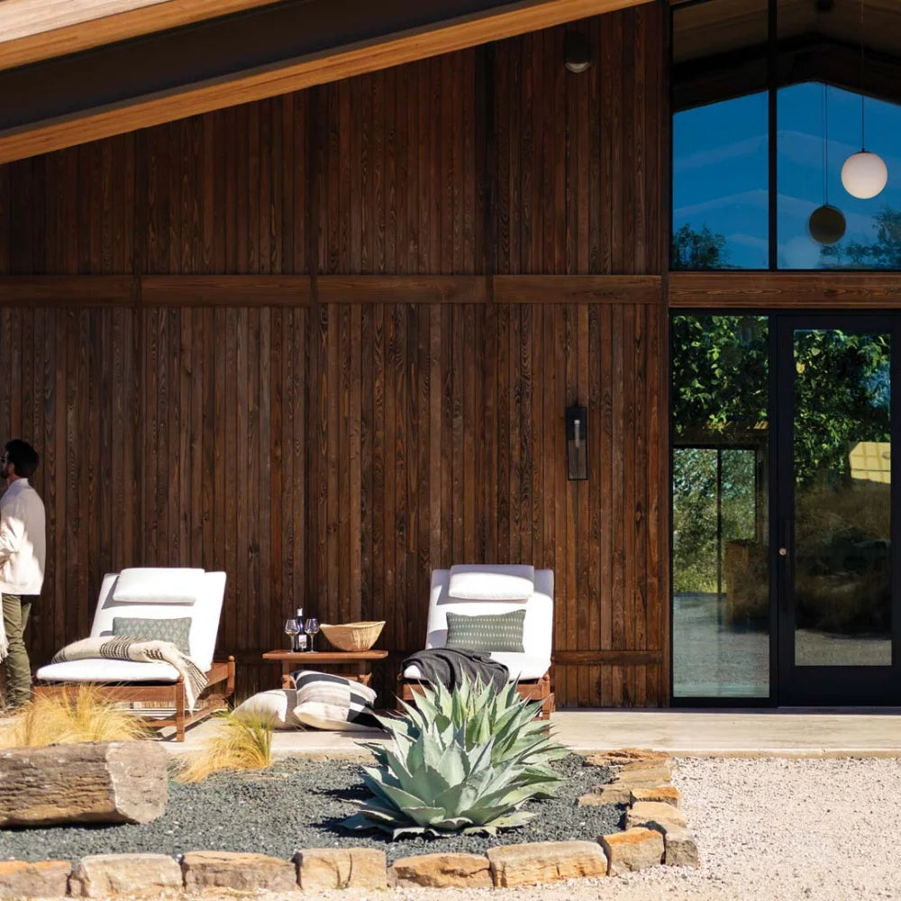Outdoor seating area in front of a modern wooden building with a glass door.