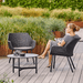 Boxhill's Vibe black outdoor armchair with a woman sitting on it and grey outdoor round table set in patio