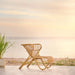 Natural rattan outdoor lounge chair with a curved woven frame on a seaside patio.