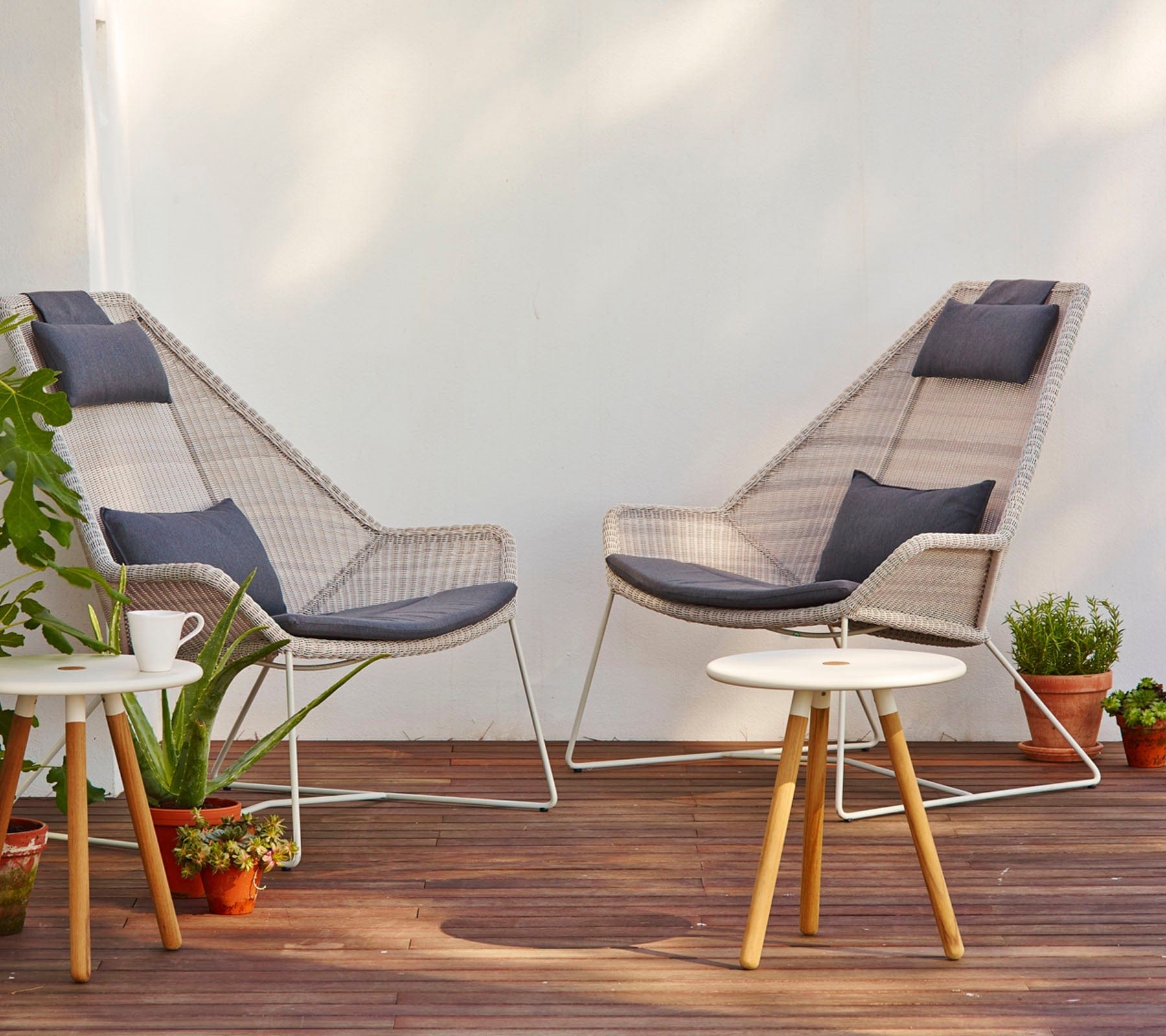 Boxhill's Breeze Highback Outdoor Chair White Grey lifestyle image on wooden platform with Area Coffee Table Chair