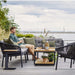 Boxhill's Ocean Outdoor Single Module Sofa lifestyle image with other Ocean Module Sofa and Chair Collection, Level Coffee Table with Teak Top and a man sitting holding a cup of coffee