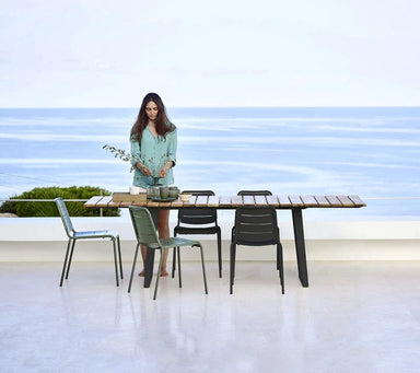 Boxhill's Copenhagen Coastal Dining Table lifestyle image at seafront with Copenhagen Dining Chair and  a woman standing beside