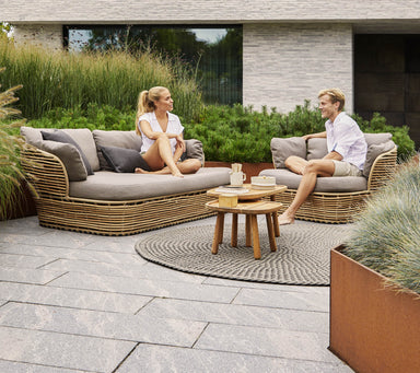 Boxhill's Basket 2-Seater Outdoor Sofa Natural lifestyle image at the garden with man and woman sitting down