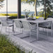 Boxhill's Breeze Dining Weave Chair Light Grey lifestyle image with dining table on wooden platform beside glass wall