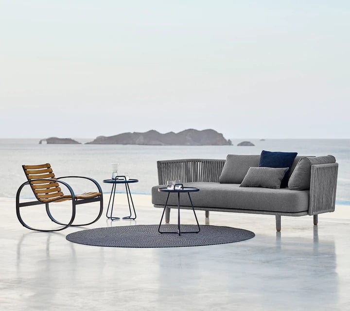 Boxhill's Moments 3-Seater Sofa lifestyle image with Parc Outdoor Rocking Chair and 2 round table at seafront