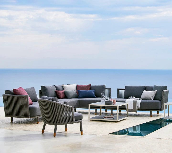 Boxhill's Moments Outdoor Corner Module lifestyle image with Moments 2-Seater Left and Right Module Sofa, Moments Outdoor Lounge Chair and Level Coffee Table beside the pool   