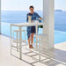 Boxhill's Cut Outdoor Aluminum Bar Table White lifestyle image with Cut High Outdoor Bar Chair and a woman standing beside the pool
