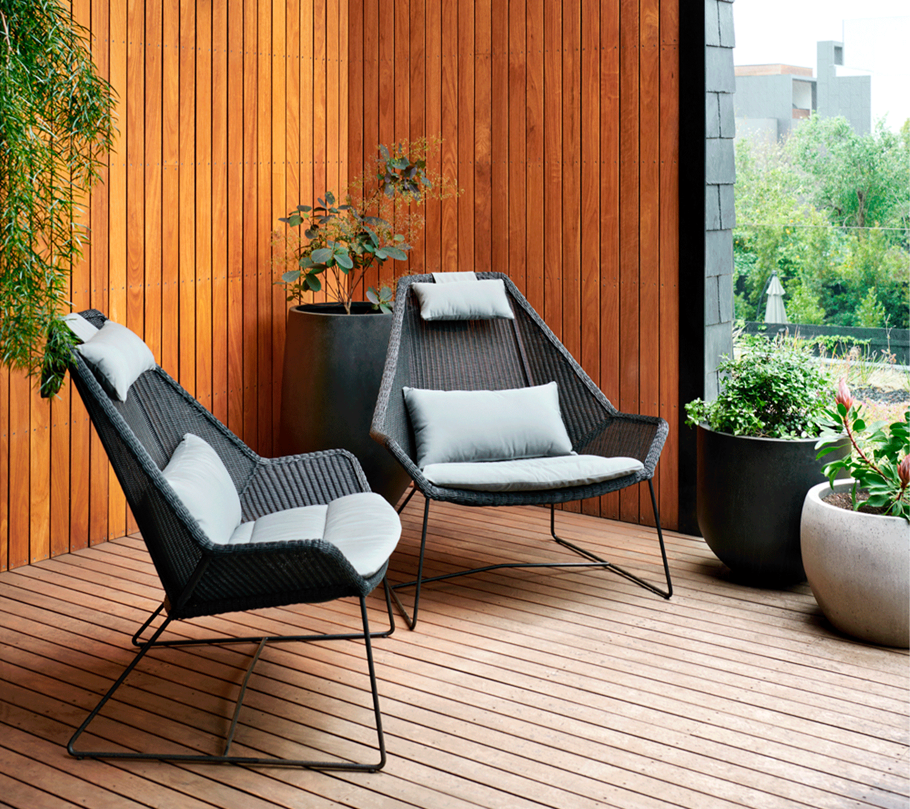 Boxhill's Breeze Highback Outdoor Chair Black lifestyle image on wooden platform beside plants