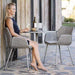 Boxhill's Vibe light grey / dusty rose outdoor armchair with a woman sitting on it and light grey round outdoor table 