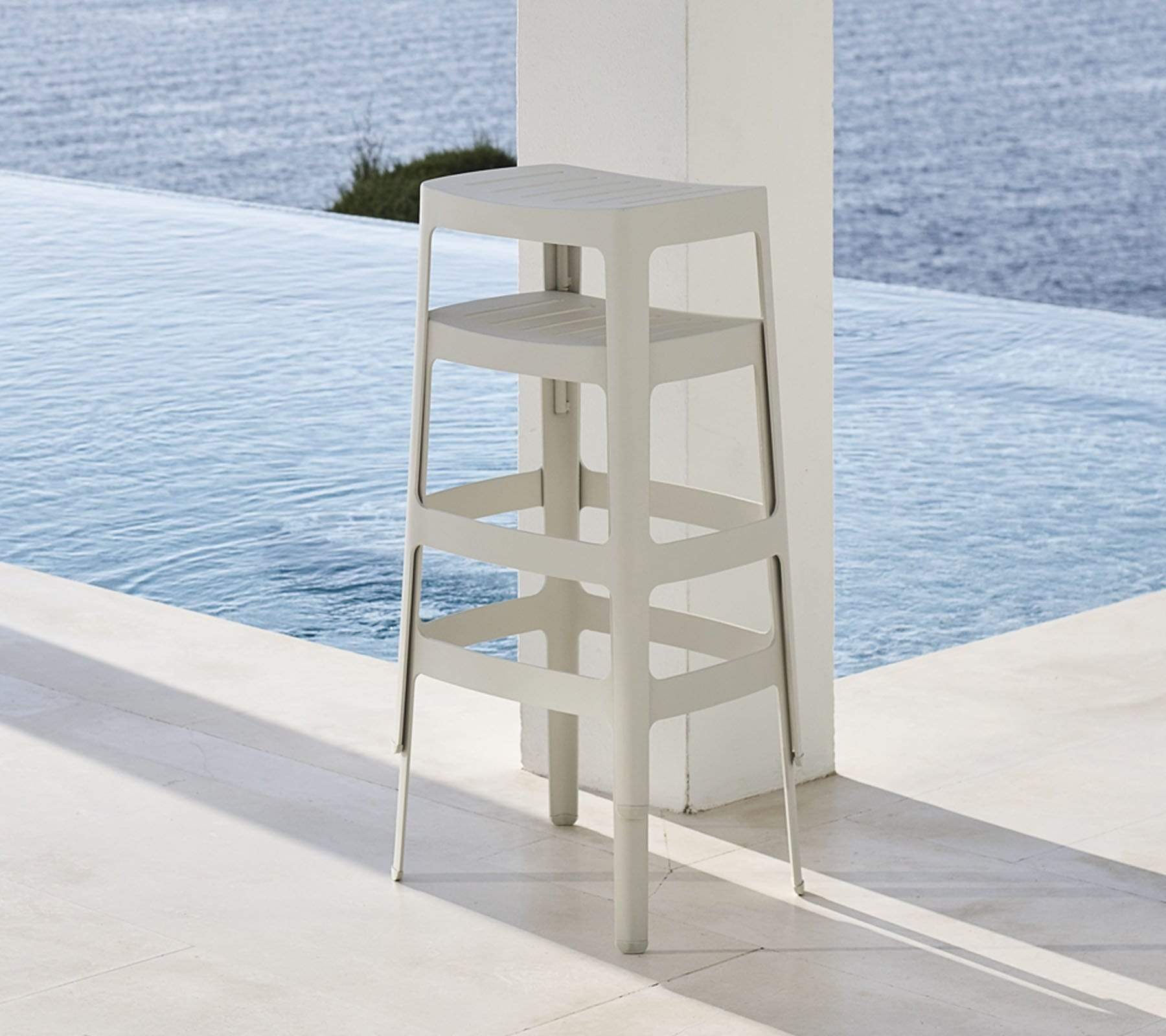 Boxhill's Cut High Outdoor Bar Chair White lifestyle image piled up beside the pool