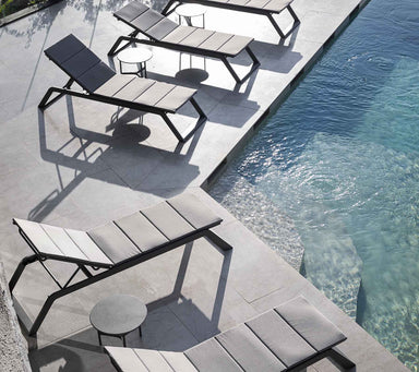 Boxhill's Siesta grey outdoor chaise lounge with grey outdoor round side table set beside the pool