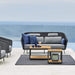 Boxhill's LEVEL Square Coffee Table Lava Grey with Teak Table Top lifestyle image with 2-seater sofa and 2 lounge chairs beside the pool 