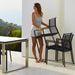 Boxhill's Edge Stackable Outdoor Armchair lifestyle image with a woman putting the chair on a pile
