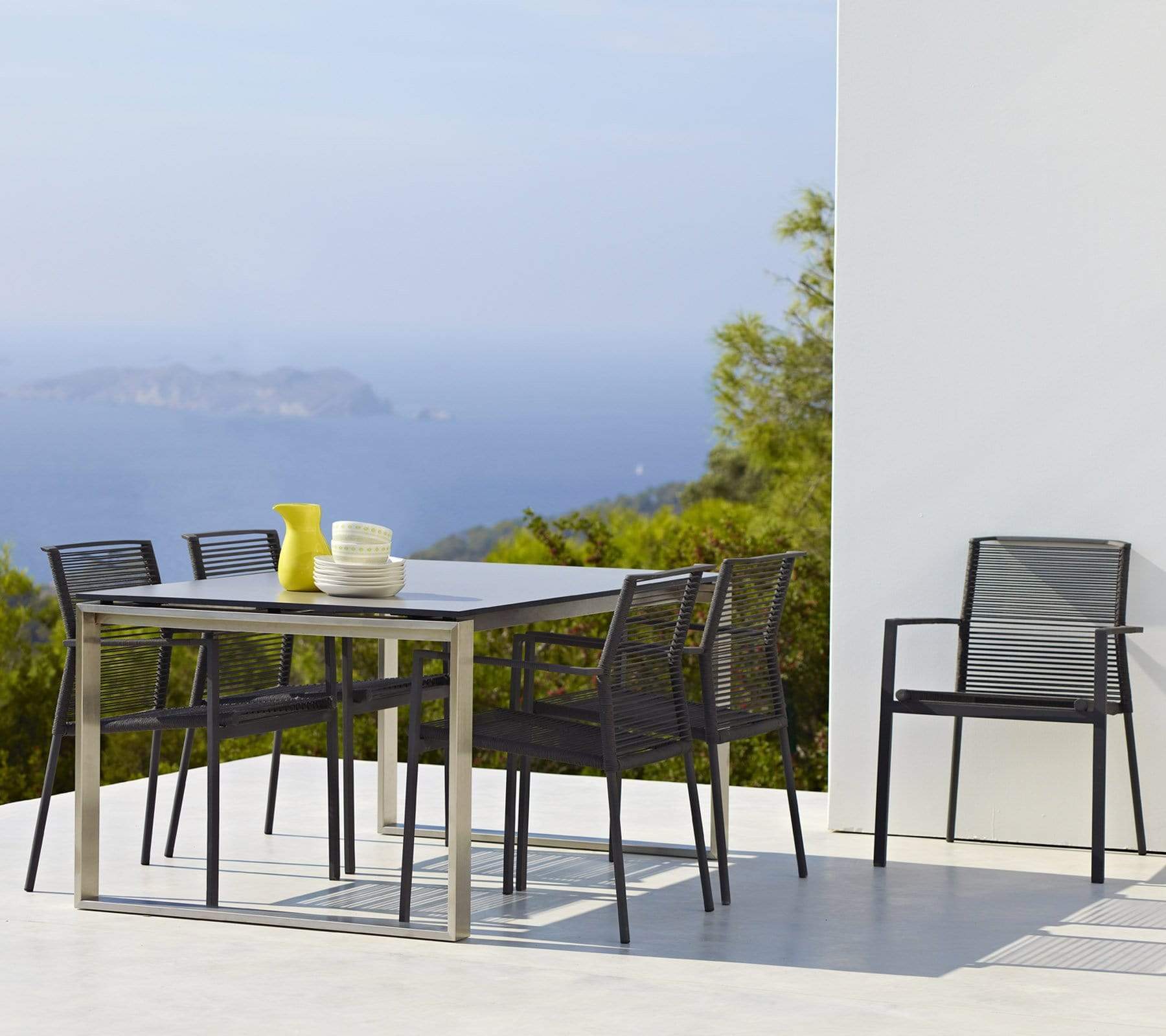 Boxhill's Edge Stackable Outdoor Armchair lifestyle image with dining table at patio