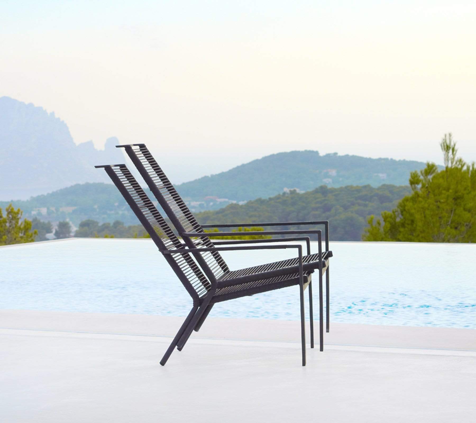 Boxhill's Edge Stackable Pool Side Highback Chair lifestyle image piled up beside the pool