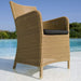 Boxhill's Hampsted Outdoor Dining Armchair natural weave with black cushion lifestyle image at beach shore