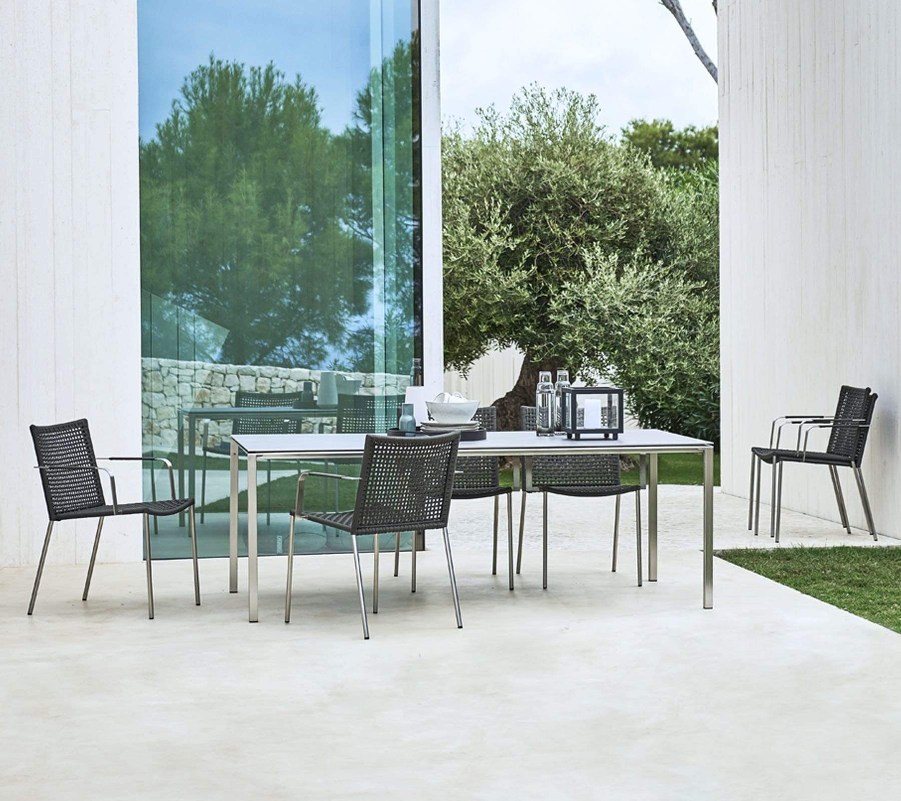  Boxhill's Straw black armchair stainless steel frame with light grey outdoor dining table placed in patio