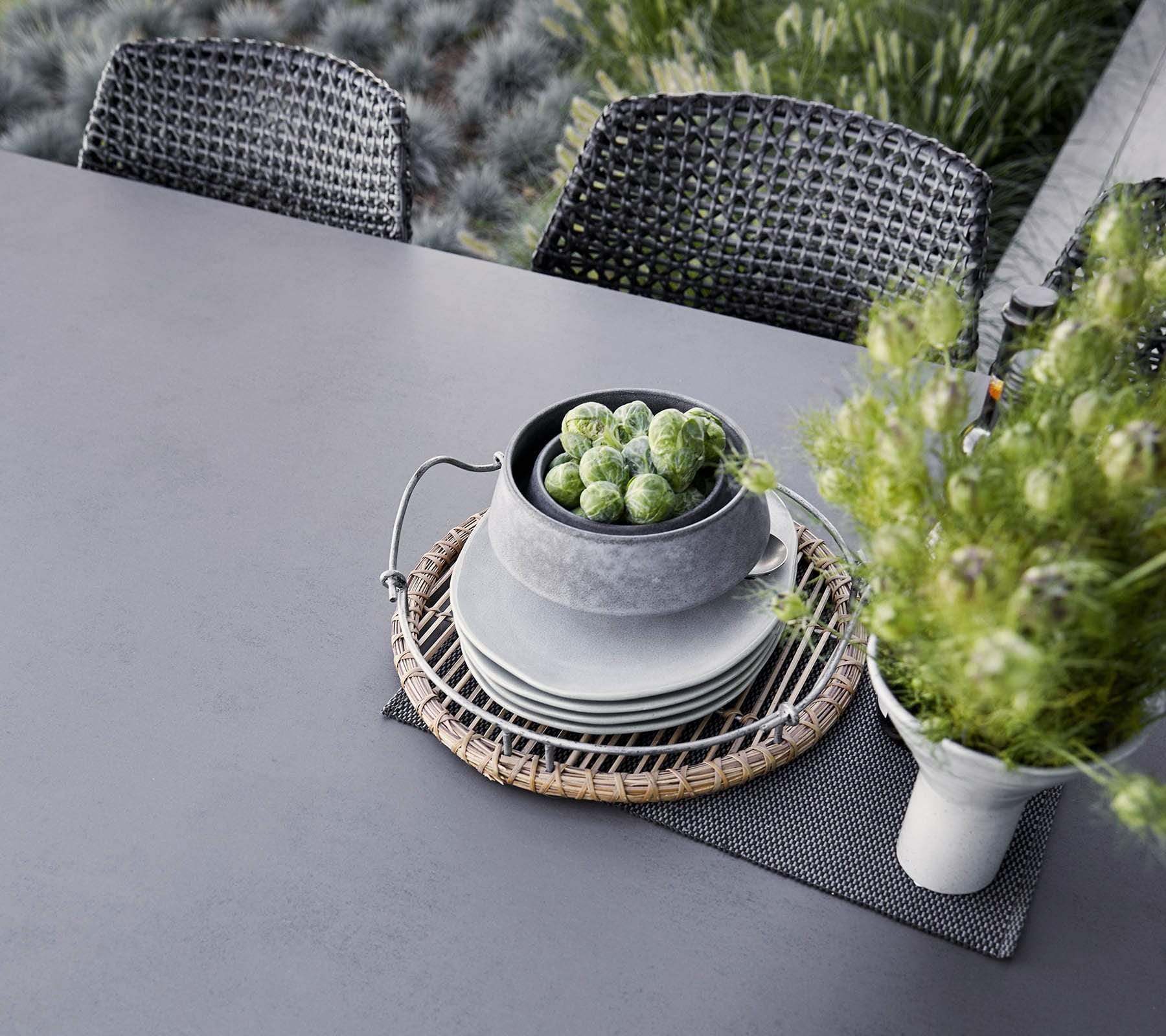 Boxhill's Vibe black outdoor armchair with dark grey outdoor dining table pile of plates and bowl on it
