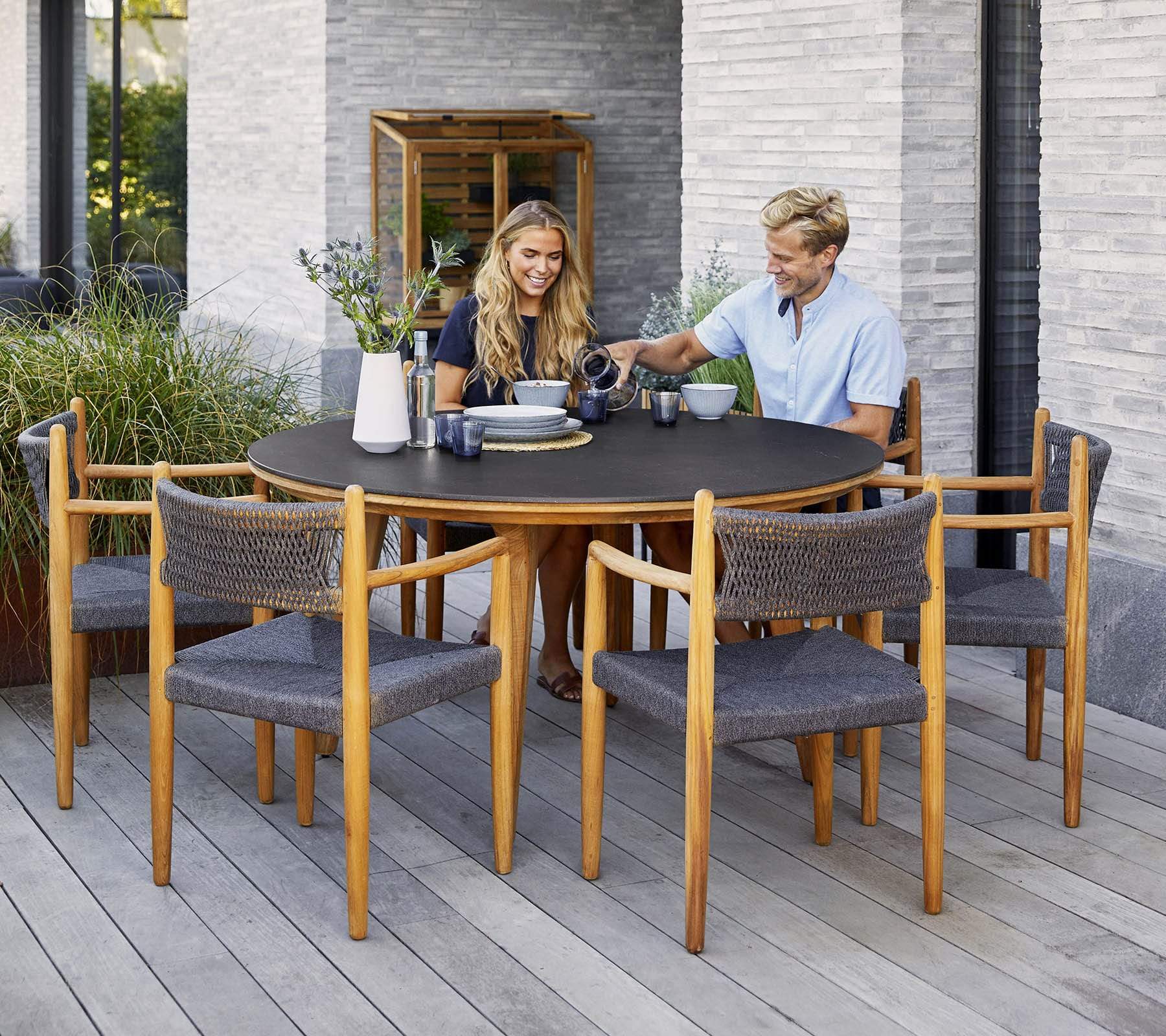 Boxhill's Aspect Teak Round Dining Table Fossil Black lifestyle image with man and woman sitting down