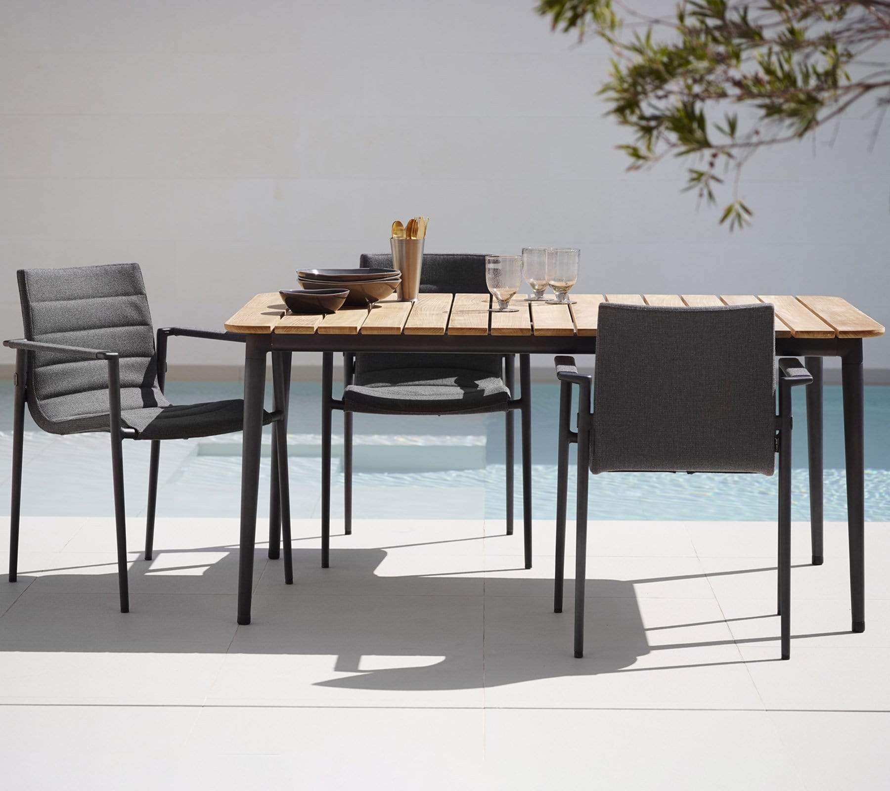Boxhill's Core Garden Dining Table Lava Grey lifestyle image with Core Patio Dining Chair beside the pool