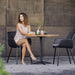 Boxhill's Drop Square Outdoor Cafe Table Lava Grey Base Teak Top lifestyle image with 2 dining chairs and a woman sitting down holding a cup