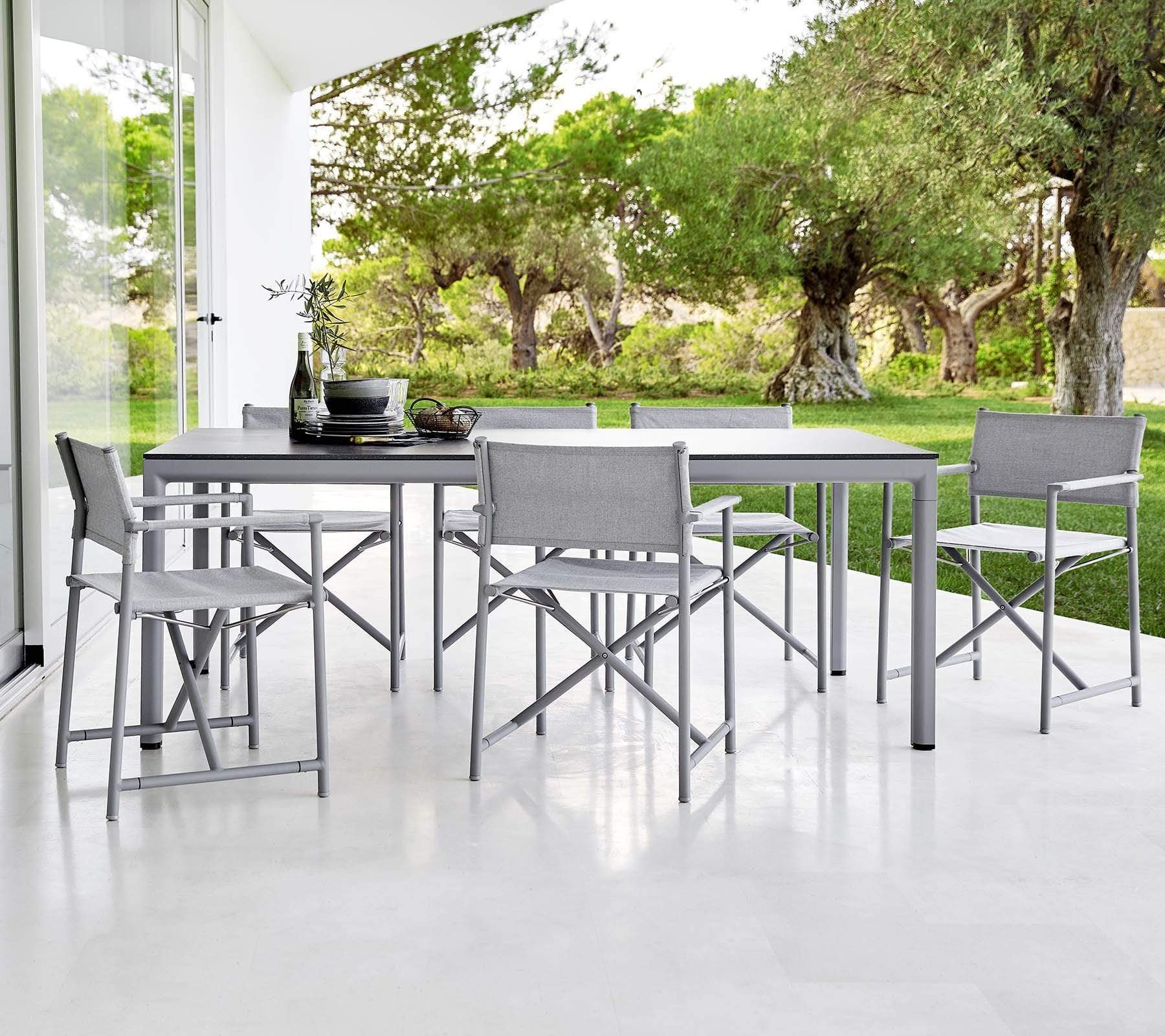 Boxhill's Drop Outdoor Dining Table Light Grey lifestyle image with dining chairs beside glass wall at patio