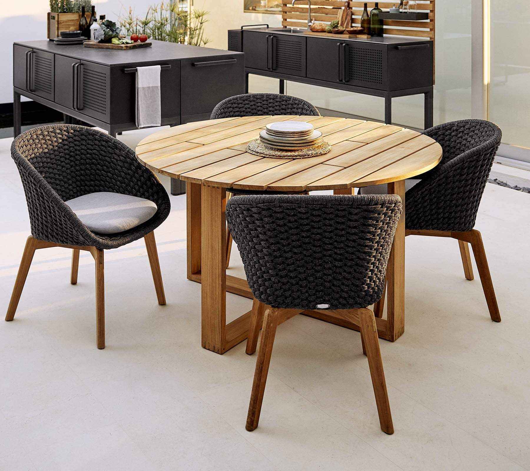 Boxhill's Endless Outdoor Round Dining Table lifestyle image with 4 dining chairs and Drop Outdoor Kitchen Module behind