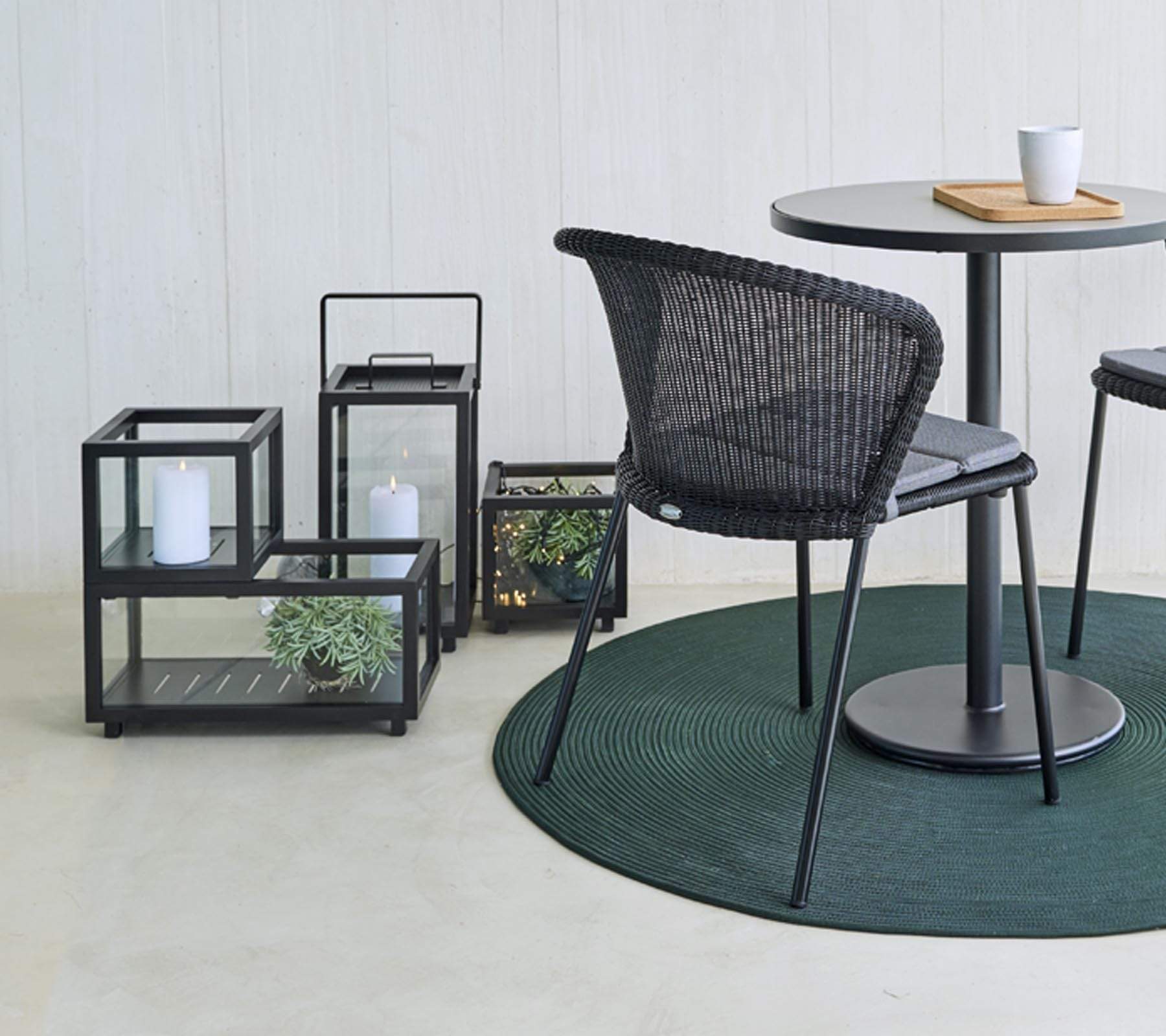Boxhill's lava grey outdoor rectanglular light box with plants on it beside black outdoor dining chair and grey round table