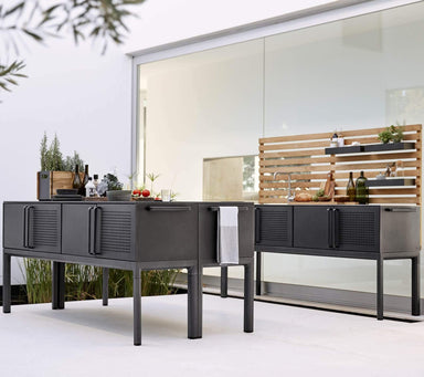 Boxhill's Drop Outdoor Kitchen Module with 3 Shelves and Teak Wall lifestyle image beside glass wall