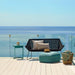 Boxhill's Time-Out aqua green outdoor side table with black outdoor 2-seater sofa and aqua green footstool with sea view background