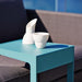Boxhill's Time-Out aqua green outdoor side table with white cup on it and dark grey outdoor sofa