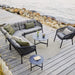 Ocean 2-Seater Outdoor Right Module Sofa lifestyle image with other Ocean Module Sofa Collection, Ocean Outdoor Lounge Chair and 2 round table on wooden platform beside rocky seashore