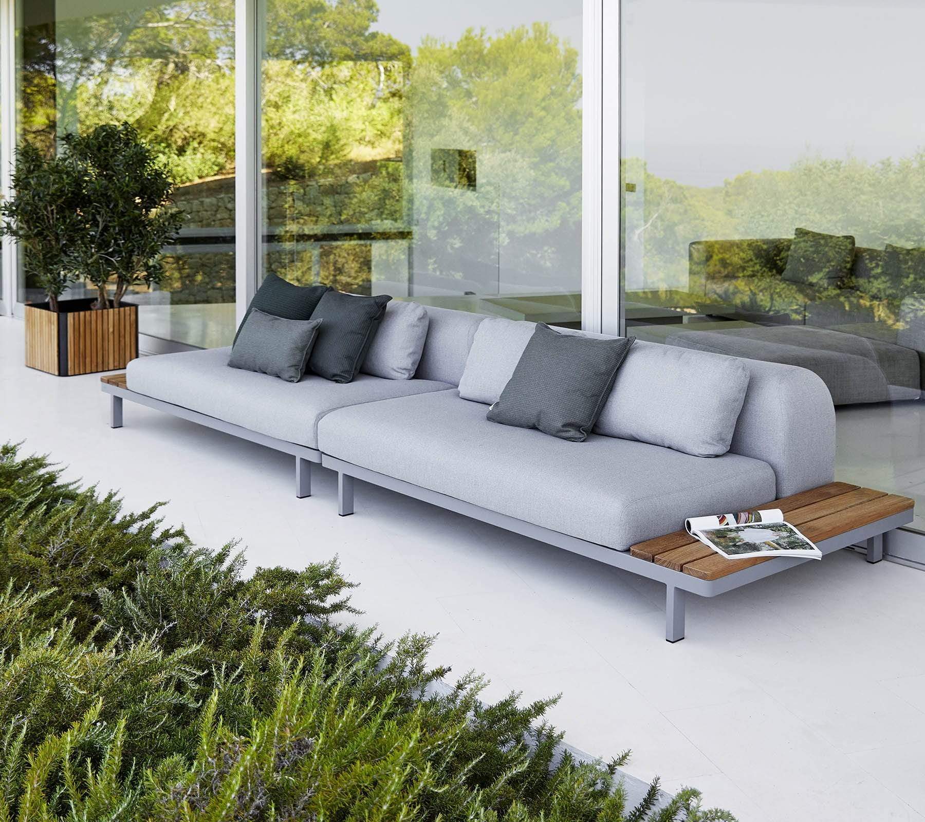 Boxhill's Space light grey outdoor sectional sofa with teak side table top set against glass wall with teak planter box at the side