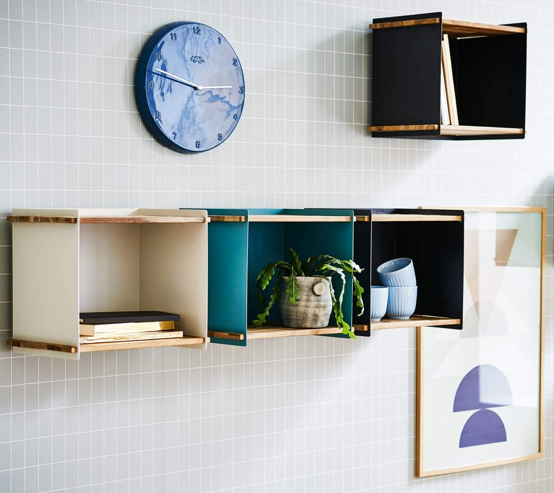 Boxhill's blue / black / white Wall-mounted Teak Wood Square Shelves mounted on grey wall tiles with random things on it and a wall clock